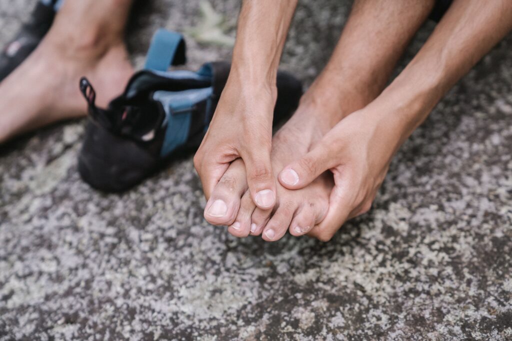 Close-up of hands grasping each other on a rough rock surface, suggesting teamwork or support during an outdoor activity